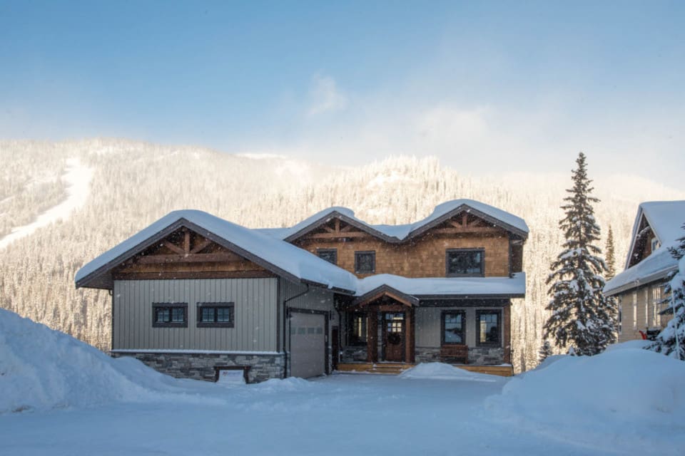 Outside entrance to a timber frame log home surrounded by snow